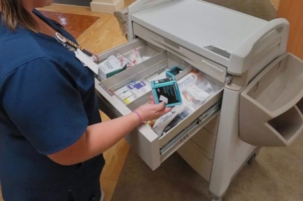 Healthcare professional organizing supplies on a clinical procedure cart